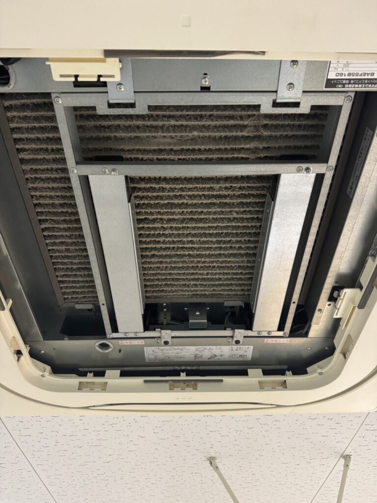 パネルを外した天井カセット形エアコン内部の汚れた熱交換器
