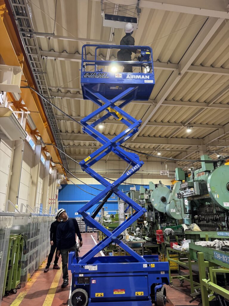 高所作業車を使って工場の天井の空調機器を作業する様子