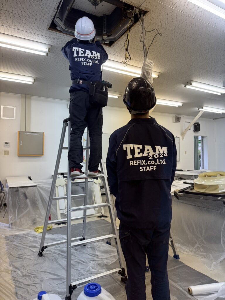 事務所の天井カセット形エアコンのパネルを外して作業するREFIXのスタッフ