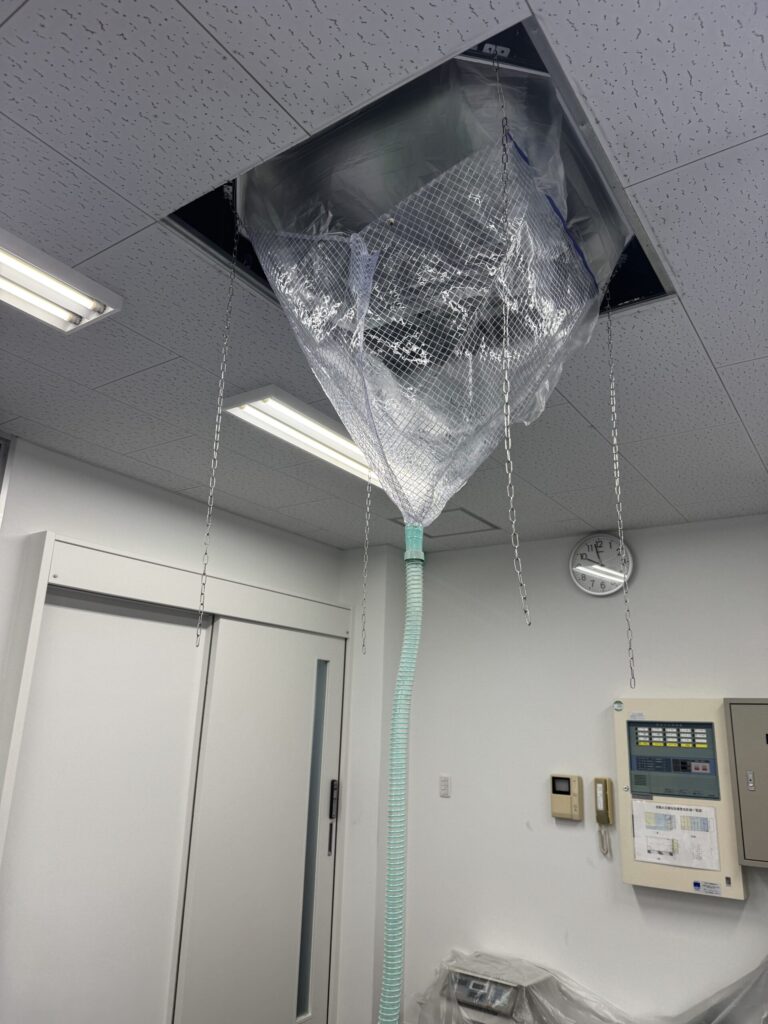 事務所の天井カセット形エアコンを高圧洗浄している様子