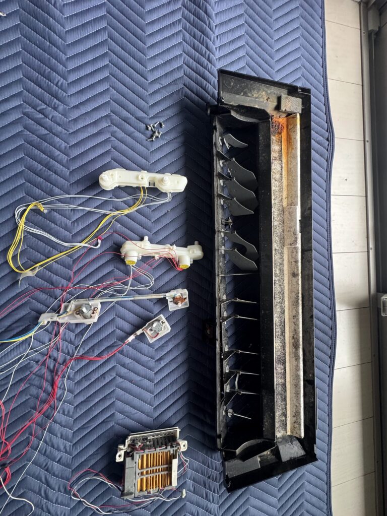 分解した壁掛けエアコンのドレンパンと電装部品